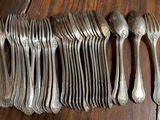 a lot of silver spoons and forks on a wooden table