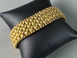 a close up of a gold bracelet on a black pillow