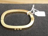 a close up of a gold bracelet with a tag on it