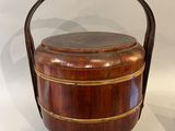 an old wooden bucket with a handle on display on a white surface