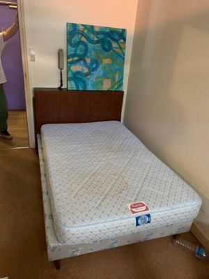 un homme debout près d'un lit dans une chambre