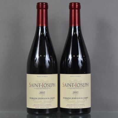 deux bouteilles de vin rouge sont posées sur une table en verre