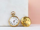 une montre de poche en or posée à côté d'un bloc de marbre blanc