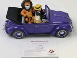 a figurine of two people in a purple car