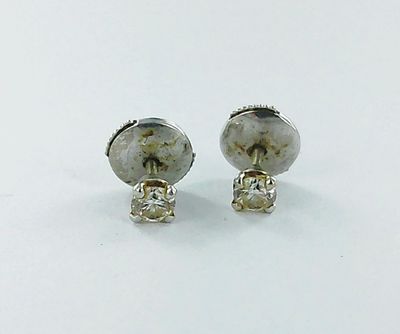 une paire de boucles d'oreilles à clous en argent et pierres blanches sur un fond blanc