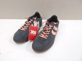 Des baskets grises et orange avec des lacets roses sont posées sur une surface blanche
