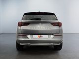 the rear end of a silver car in a white room
