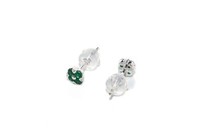 une paire de boucles d'oreilles à clous en cristal vert et blanc sur fond blanc