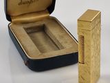 un briquet doré posé à côté d'un étui noir sur une table