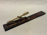 une vieille maquette de télescope en laiton et en bois posée sur une surface blanche