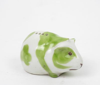 une figurine d'animal verte et blanche posée sur une surface blanche