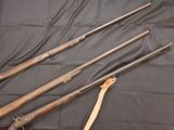 three old guns are lined up on a black cloth