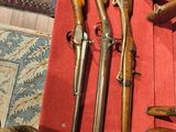beaucoup d'armes à feu posées sur une table rouge