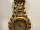 a gold clock hanging on the wall next to a wall clock