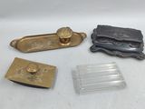 trois objets en laiton et en verre sont posés sur une surface blanche