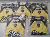quatre maillots de foot jaunes et noirs dans des sacs en plastique posés sur une table
