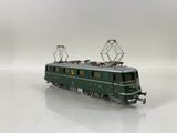 a green train that is on the tracks on a white surface