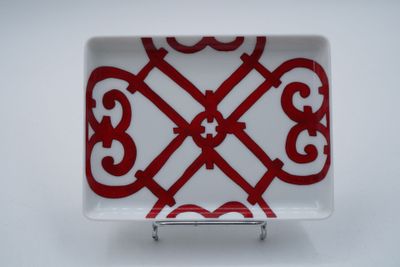 assiette rouge et blanche ornée d'un motif, posée sur un support métallique