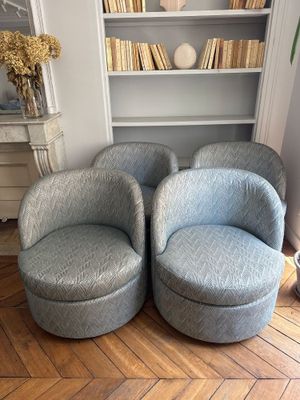 une paire de fauteuils pivotants bleus dans un salon, avec une bibliothèque en arrière-plan