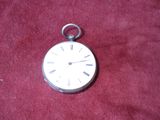 a silver pocket watch sitting on a red cloth