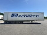 une semi-remorque blanche garée sur un parking, arborant sur le côté le logo Pedretti bleu et blanc