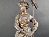 bronze statue of a woman with a rake and a basket of flowers