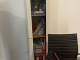 a chair that is next to a book shelf in a room