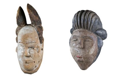 On voit deux masques en bois sur un fond blanc ; l'un représente un visage d'homme et l'autre un visage de femme.