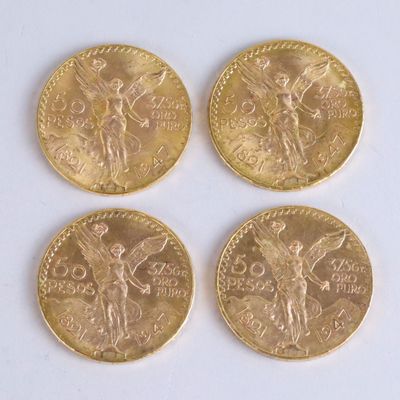 four gold coins sitting on top of each other on a white surface