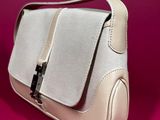 the white purse is sitting on a pink surface with a pink background