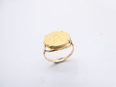 a gold ring with a coin on top of it