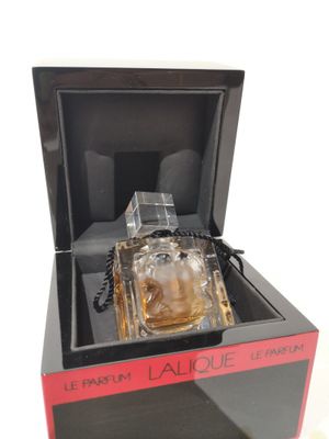 un flacon de parfum dans une boîte noire posé sur une surface blanche