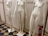 trois mannequins debout dans une pièce dont le sol est en damier noir et blanc