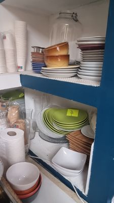 many plates and bowls on the shelves in the kitchen