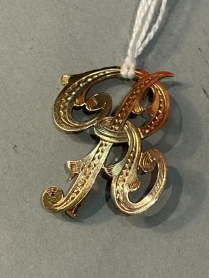 a silver and gold brooch on a white string