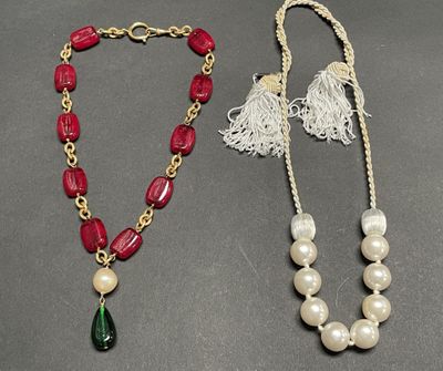 two necklaces with pearls and a tassel on a table