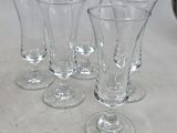 four empty wine glasses sitting on top of a table next to a pitcher