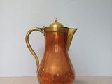 a copper pitcher sitting on a table with a white background