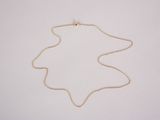 the gold necklace is on a white surface with a gold chain around it