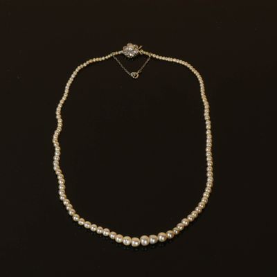 un collier de perles blanches avec un fermoir en diamant