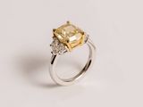 a close up of a yellow and white diamond ring on a white surface