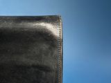 black leather purse on blue background with copy space for text