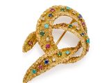 un gros plan sur une broche en or sertie de pierres multicolores