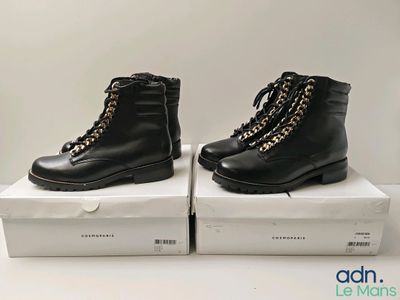 two pairs of black boots with gold chains on them sitting on a box