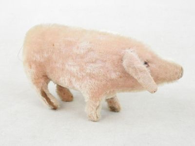 un petit cochon en peluche debout dans la neige