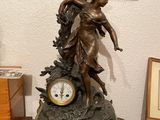 une statue de femme tenant une horloge sur une table