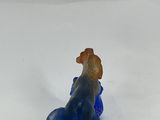 blue glass figurine of a dog sitting on a rock on a white surface