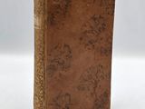 an old book with a brown cover sitting on top of a white table