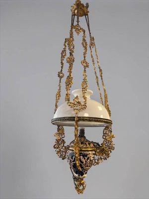 an old fashioned hanging lamp with a white and gold shade