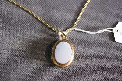 a close up of a gold necklace with a white stone on it